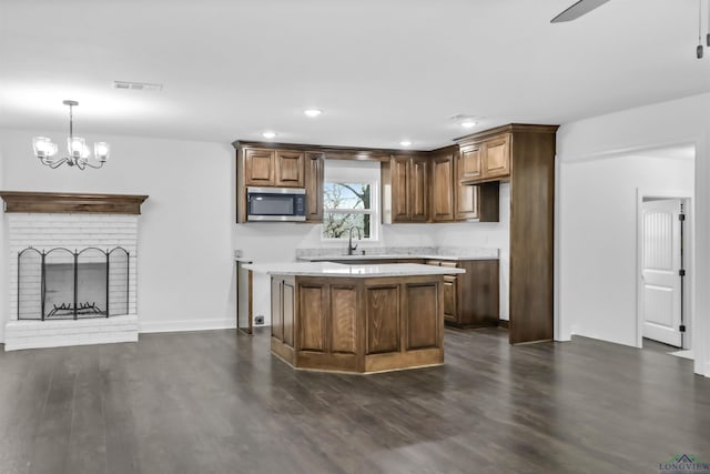 kitchen with a fireplace, a center island, hanging light fixtures, and dark hardwood / wood-style floors