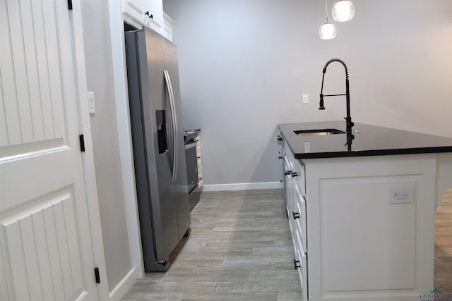 kitchen with white cabinetry, sink, hanging light fixtures, stainless steel fridge with ice dispenser, and light hardwood / wood-style floors