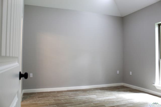 empty room with light hardwood / wood-style flooring and vaulted ceiling