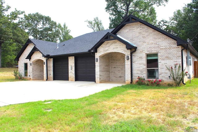 french country home featuring a garage and a front lawn