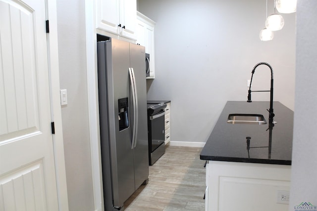 kitchen featuring white cabinetry, sink, stainless steel appliances, light hardwood / wood-style flooring, and pendant lighting