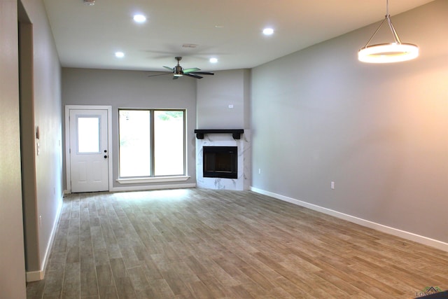 unfurnished living room featuring hardwood / wood-style floors, ceiling fan, and a fireplace