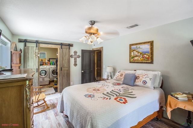 bedroom featuring washer and clothes dryer, ceiling fan, a barn door, and light hardwood / wood-style floors