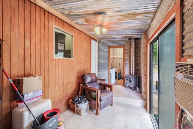 living area with a wood stove, wooden ceiling, wooden walls, vaulted ceiling, and light tile patterned floors