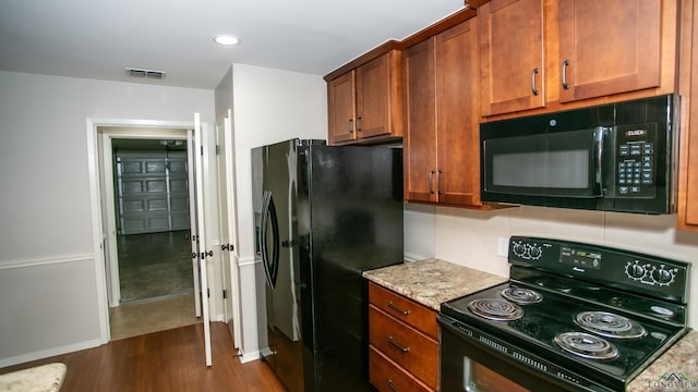 kitchen with light stone countertops, dark hardwood / wood-style flooring, and black appliances