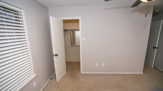 unfurnished bedroom with ceiling fan, light colored carpet, and a spacious closet