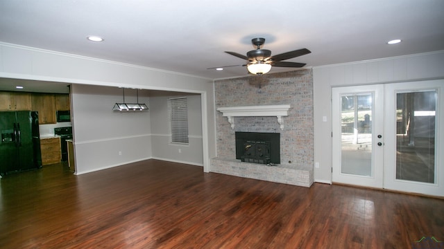 unfurnished living room featuring ceiling fan, french doors, dark hardwood / wood-style floors, crown molding, and a fireplace