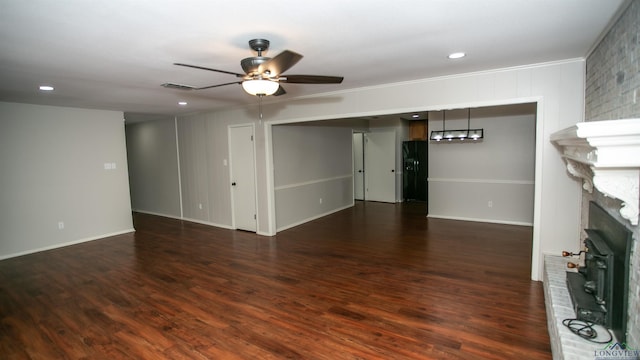 unfurnished living room with crown molding, ceiling fan, a fireplace, and dark wood-type flooring