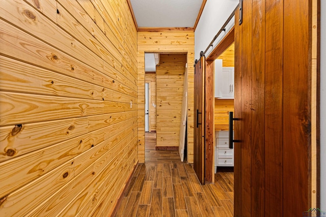 corridor featuring wood walls, a barn door, and wood-type flooring