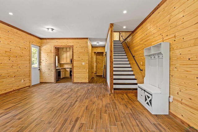 unfurnished living room featuring crown molding, wooden walls, and wood-type flooring