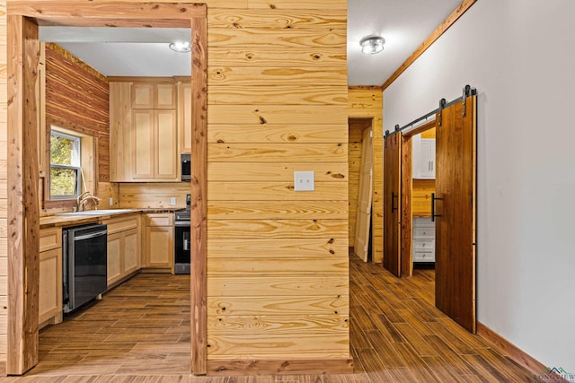 kitchen featuring light brown cabinets, a barn door, hardwood / wood-style floors, wooden walls, and ornamental molding