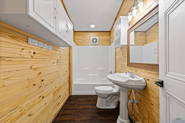 bathroom featuring wooden walls, hardwood / wood-style floors, shower / bath combination, and toilet