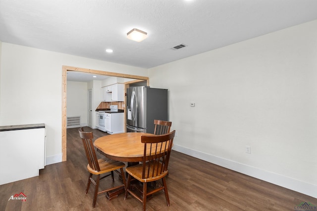 dining space with dark wood-type flooring and a textured ceiling