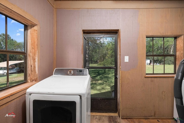 laundry area featuring hardwood / wood-style floors, washer / clothes dryer, and a healthy amount of sunlight