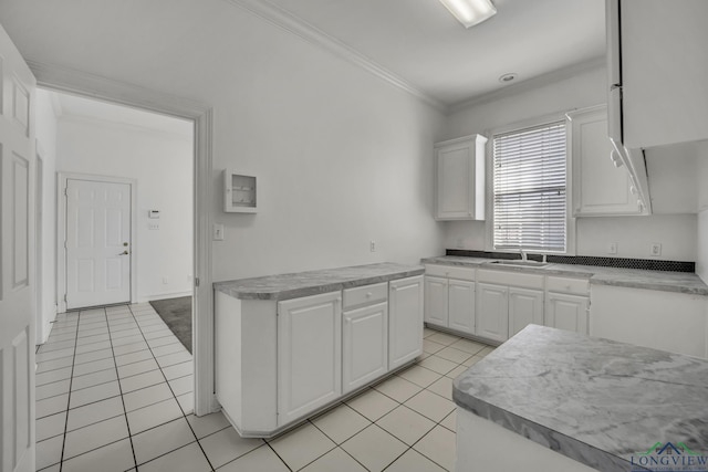 kitchen featuring white cabinets, light tile patterned floors, crown molding, and sink