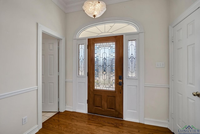 foyer featuring hardwood / wood-style floors, an inviting chandelier, a wealth of natural light, and crown molding