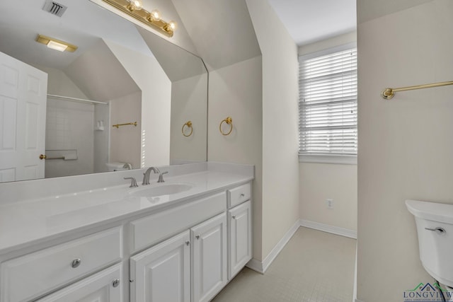 bathroom featuring vanity, toilet, and vaulted ceiling