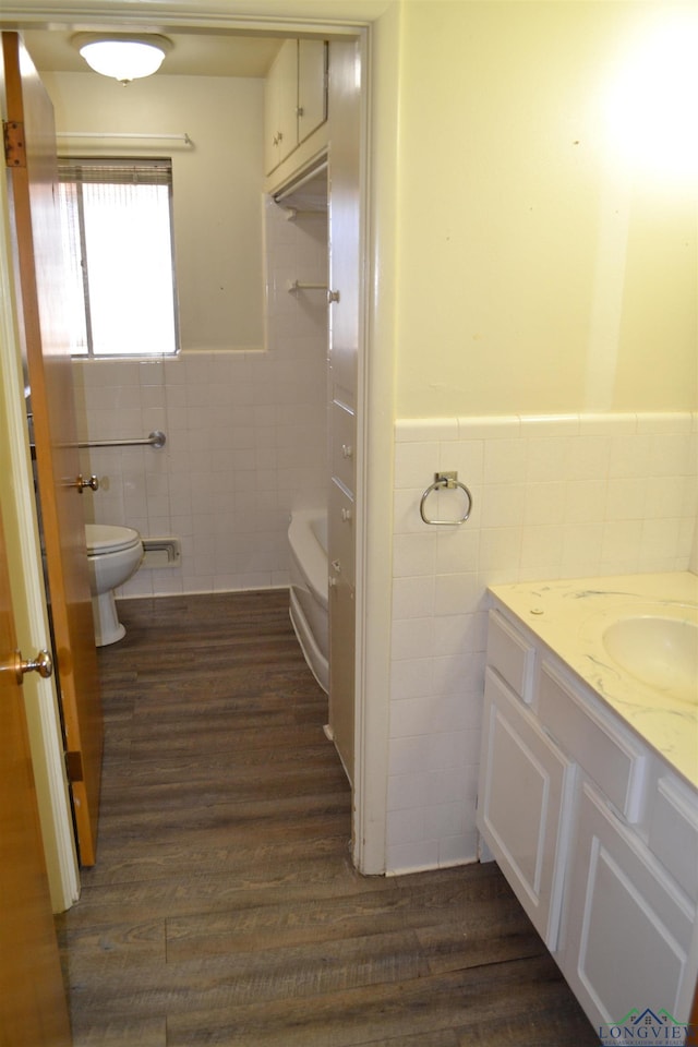 bathroom with hardwood / wood-style flooring, vanity, toilet, and tile walls