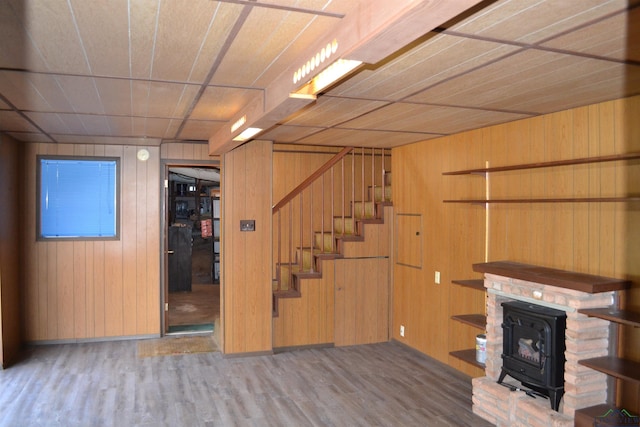 basement with wood-type flooring, a wood stove, and wood walls