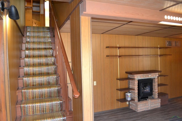 stairway with hardwood / wood-style floors, a wood stove, and wood walls