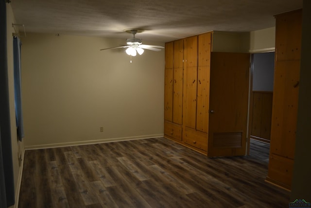 unfurnished bedroom with wooden walls, ceiling fan, and dark hardwood / wood-style floors