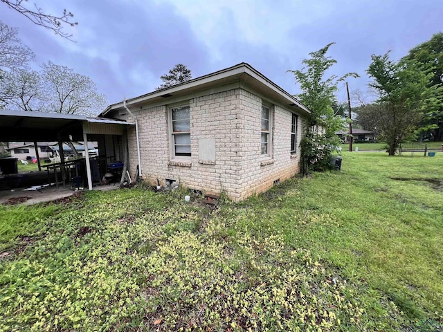 view of side of home with a carport and a lawn