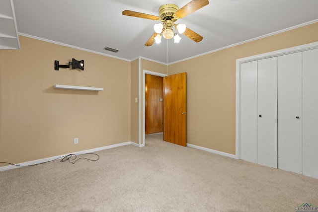 unfurnished bedroom with crown molding, carpet, baseboards, visible vents, and a closet