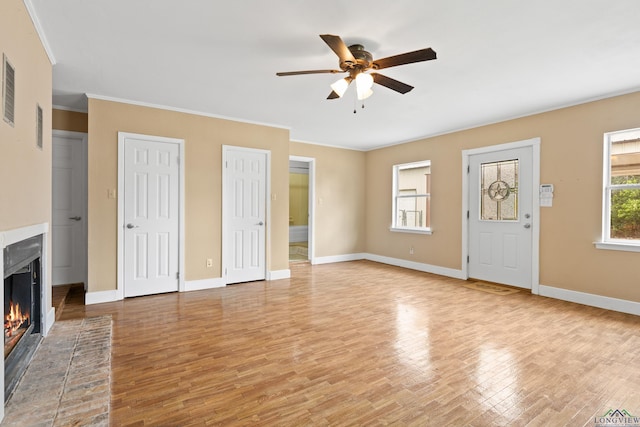 unfurnished living room featuring ornamental molding, a brick fireplace, baseboards, ceiling fan, and light wood finished floors