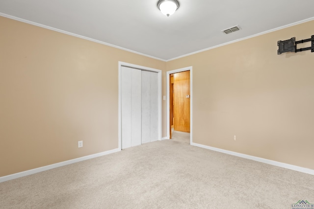 unfurnished bedroom with crown molding, carpet floors, visible vents, a closet, and baseboards