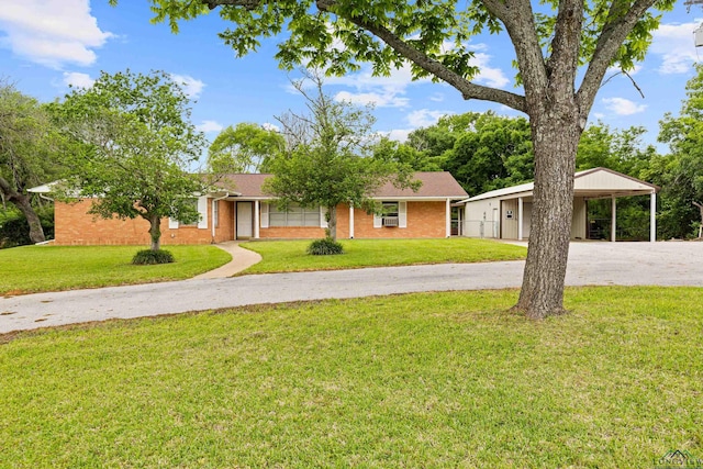 ranch-style home featuring brick siding, driveway, a front yard, and a carport