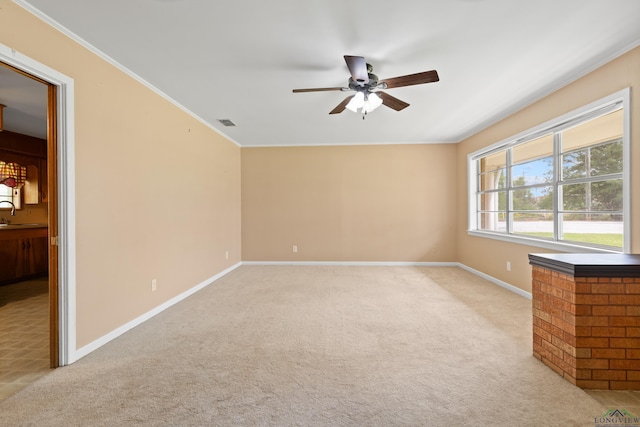spare room featuring crown molding, visible vents, baseboards, light colored carpet, and a ceiling fan