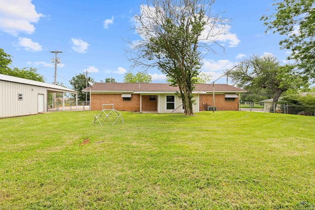 back of property with fence, a yard, and brick siding