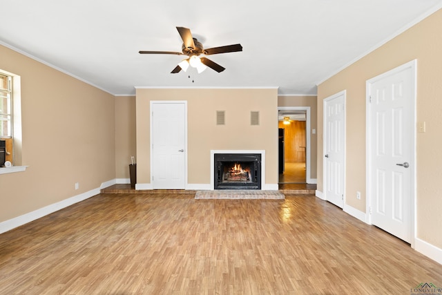 unfurnished living room with ceiling fan, crown molding, a fireplace, baseboards, and light wood-style floors