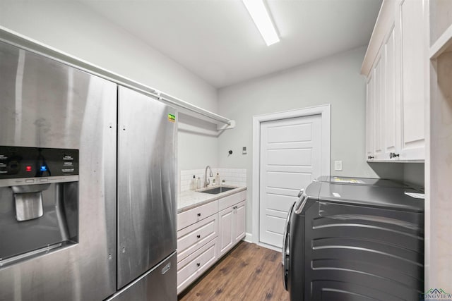 laundry area featuring dark wood finished floors, washing machine and clothes dryer, cabinet space, and a sink