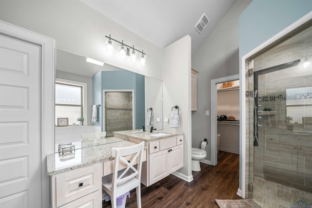 bathroom featuring visible vents, toilet, vanity, and a shower stall