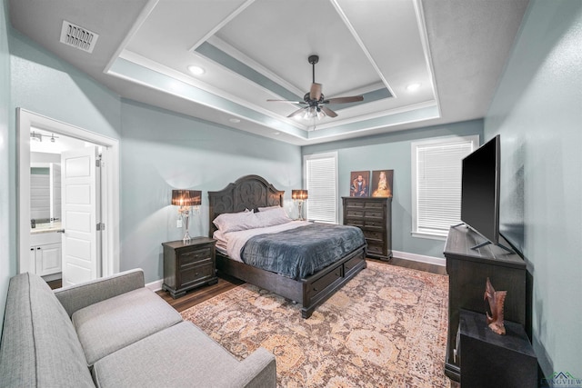 bedroom with a ceiling fan, wood finished floors, baseboards, visible vents, and a tray ceiling