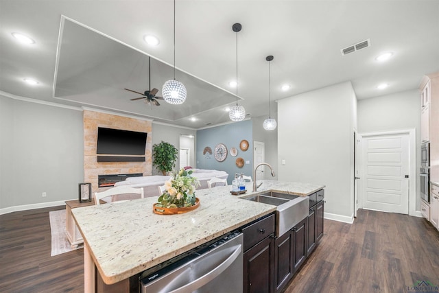 kitchen with a kitchen island with sink, stainless steel dishwasher, visible vents, a sink, and a tray ceiling