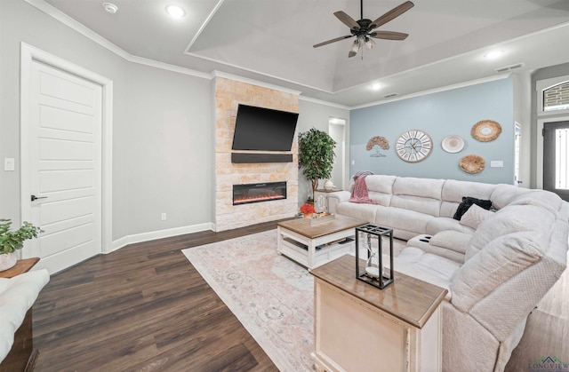 living room featuring crown molding, a raised ceiling, baseboards, a fireplace, and dark wood-style flooring