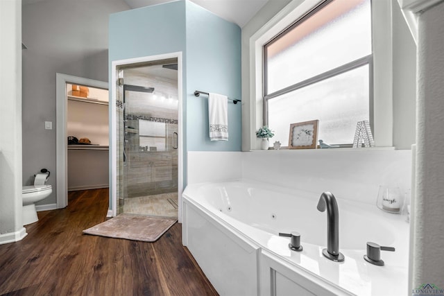 bathroom featuring wood finished floors, a jetted tub, a walk in closet, toilet, and a shower stall