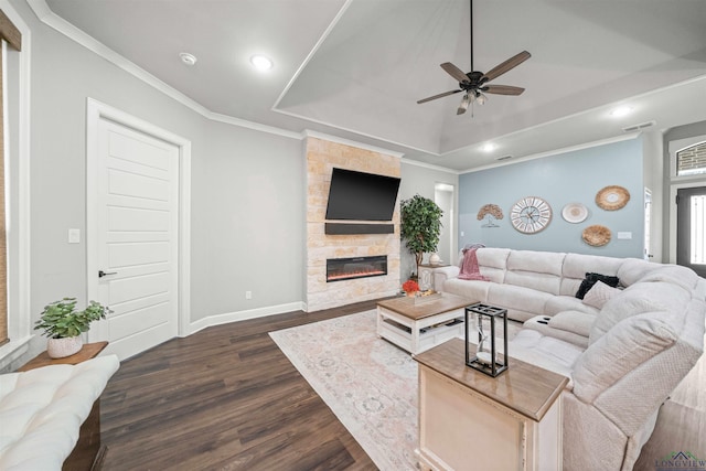 living area with a raised ceiling, dark wood-style floors, a fireplace, and crown molding