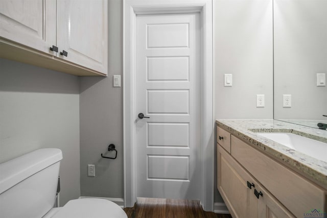 bathroom with baseboards, vanity, toilet, and wood finished floors