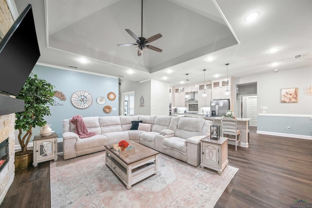 living area with a raised ceiling, visible vents, recessed lighting, a fireplace, and dark wood-type flooring