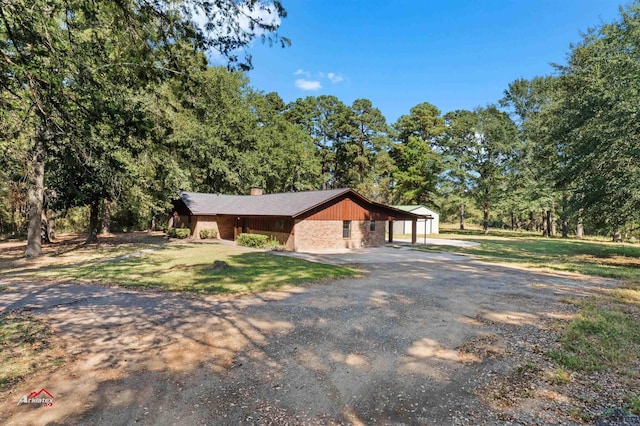 single story home featuring a garage, a front lawn, and an outdoor structure