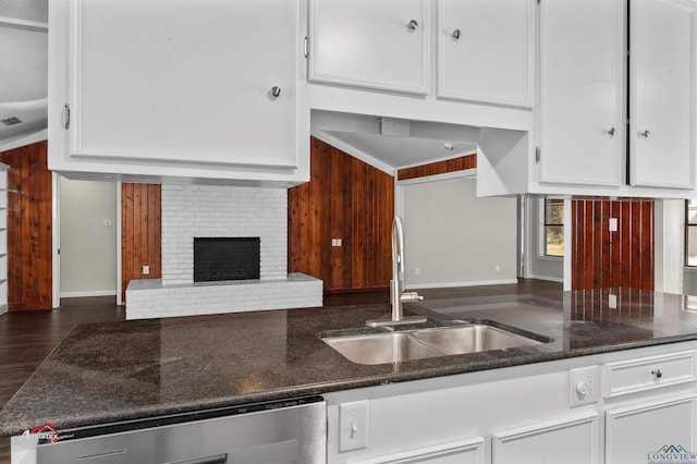 kitchen featuring white cabinetry, sink, dishwasher, and a brick fireplace