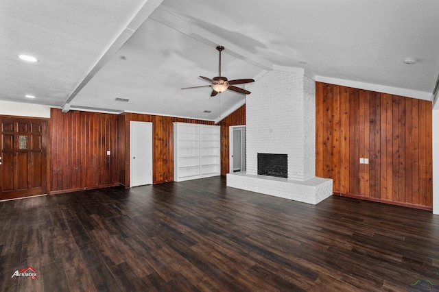 unfurnished living room with ceiling fan, a brick fireplace, lofted ceiling with beams, dark hardwood / wood-style floors, and wood walls