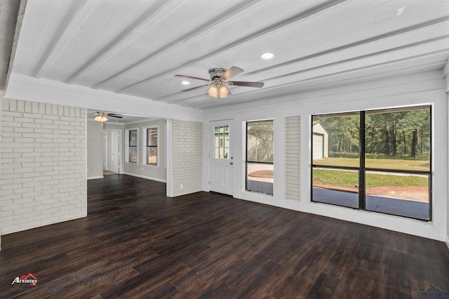 unfurnished living room with beamed ceiling, dark hardwood / wood-style flooring, ceiling fan, and brick wall