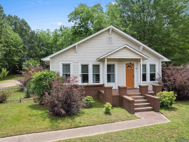 bungalow-style home featuring a front yard and fence