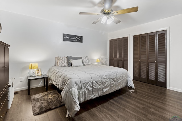 bedroom with ceiling fan, dark hardwood / wood-style floors, and multiple closets