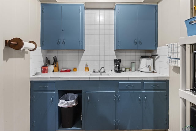 kitchen featuring backsplash, tile counters, sink, and blue cabinets