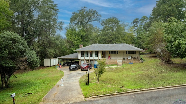 view of front of home featuring a carport, a front lawn, covered porch, and a storage shed